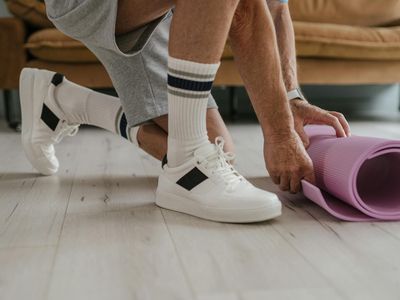 Close-up of a yoga mat and a water bottle on a wooden floor.